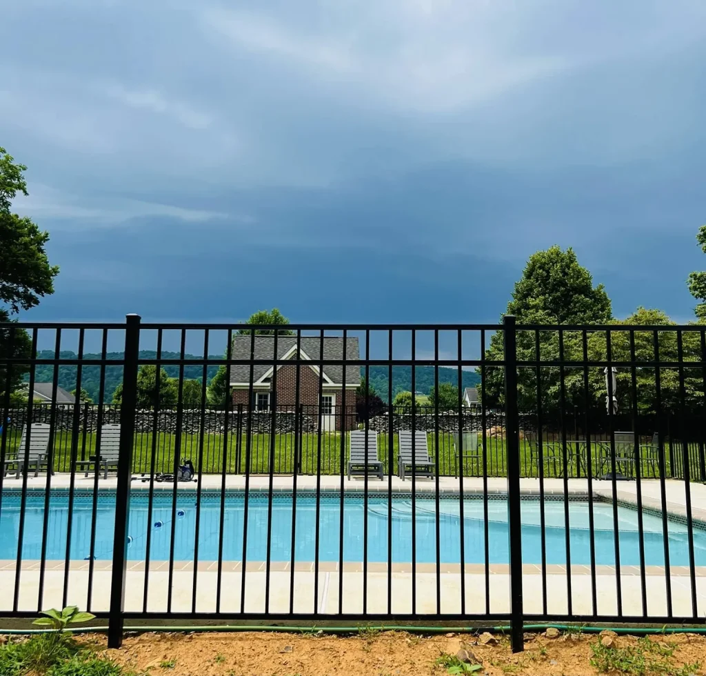 Black aluminum pool fencing with a house and backyard pool behind it