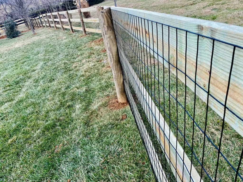 A wooden fence with metal wiring in a field
