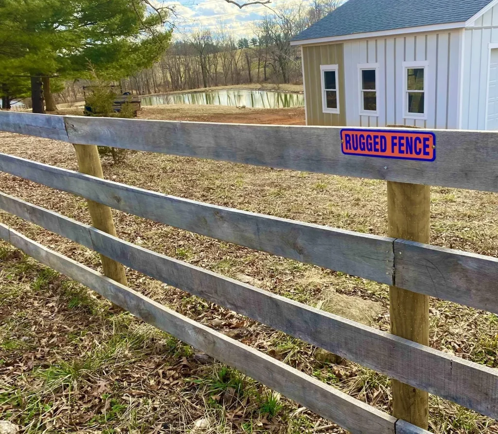 A 4-board wooden fence with the Rugged Fence logo attached to it